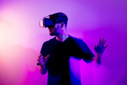 Mann mit VR-Brille vor lila HIntergrund